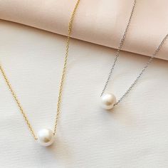 Alexandra’s single Floating Freshwater Pearl necklace evokes a classic look to any and every outfit. Simple, clean, and elegant this white pearl necklace will become your new go to! Details:• White Freshwater Pearl• 18kt Gold Plated or Rhodium Plated Sterling Silver • Chain Length: Adjustable from 16" to 18" • Pearl Size: 10mm Single Pearl Necklace Tiffany & Co., Cheap White Pearl Pendant Charm Necklace, Classic White Necklace With Delicate Chain, White Classic Necklace With Delicate Chain, Classic Pearl White Necklace With Clavicle Chain, White Pearl Necklace With Delicate Round Pendant, White Pearl Necklace With Delicate Chain And Round Pendant, Classic Pearl Necklace For Gift, Classic Pearl White Pearl Necklace As Gift