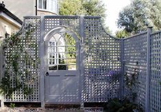 a gate that is made out of wood and has an arch in the middle with flowers growing on it