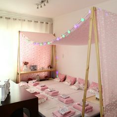 a bed with pink sheets and pillows in a room that has lights on the ceiling