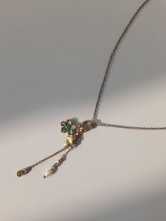 Adorn yourself with the whimsical charm of nature with this delightful necklace featuring four dangling treasures. A petite green flower, a delicate leaf, a shimmering stone, and a lustrous pearly accent sway gracefully from the dainty chain, creating a captivating ensemble that captures the essence of natural beauty. Whether worn alone or layered with other favourites, this enchanting piece adds a touch of elegance and allure to any look. Dainty Jewelry With Vintage Charm And Flower Pendant, Dainty Vintage Charm Flower Pendant Jewelry, Dainty Flower Pendant Jewelry With Vintage Charm, Dainty Flower Pendant With Vintage Charm, Charming Flower Pendant Necklace, Dainty Flower Pendant Necklace With Vintage Charm, Elegant Metal Necklaces With Dangling Charms, Dainty Metal Necklaces With Vintage Charm, Dainty Emerald Flower Charm Jewelry