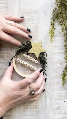 two hands are holding a wooden cross stitch ornament with gold stars on it