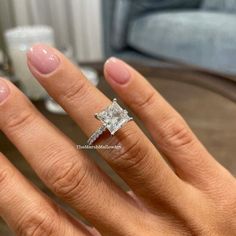 a woman's hand with a diamond ring on her finger and the other hand holding an engagement ring