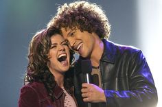 two people standing next to each other holding a microphone and singing into the microphone with their mouths open