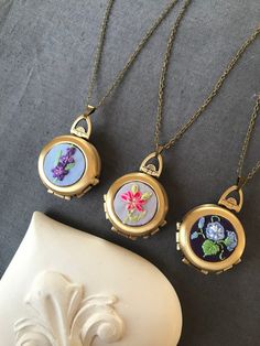 🌱10 % OFF THE WHOLE STORE WITH CODE WELCOME🌱 This gorgeous vintage style photo locket necklace decorated with a floral hand embroidery opens to reveal your photos or a secret personalized message. You can personalize the front of the locket with a hand embroidery of your favorite flower or your birth flower. I can embroider any flower you want, just leave me your custom instructions in 'add your personnalisation' box at checkout. For example: a pink rose on a light blue background. I'll send y Heirloom Handmade Vintage Necklace, Vintage Birth Flower Necklace For Wedding, Handmade Medallion Locket Necklace Keepsake, Bohemian Jewelry With Floral Embroidery For Gifts, Vintage Embroidered Jewelry, Handmade Vintage Jewelry For Mom, Handmade Brass Locket Necklace For Wedding, Vintage Round Necklace As Gift For Mom, Handmade Round Locket Necklace In Bohemian Style