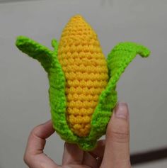 a crocheted corn cob is being held up by someone's hand