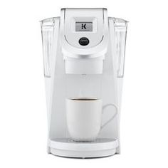 a white coffee maker with a cup in front of it