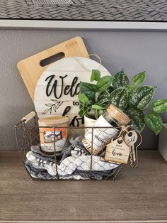 a basket filled with plants and candles on top of a wooden table next to a cutting board