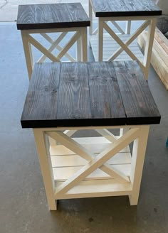 two white and black tables sitting next to each other on top of a cement floor