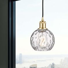 a glass light hanging over a window next to a tall building with a city in the background