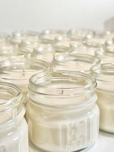 several jars filled with white candles sitting on a table