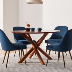 a dining room table with blue chairs and a white rug on the floor in front of it