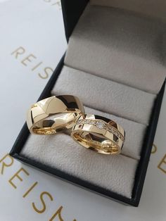 two gold wedding rings sitting in a box