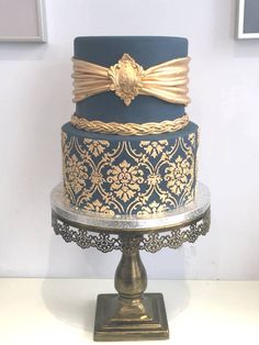 a three tiered cake with blue and gold decorations on it's top stand