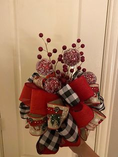 a hand holding a red, black and white christmas wreath with candy balls on it