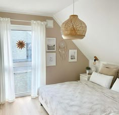 a bedroom with a large bed and white drapes on the windowsill, along with a hanging light fixture