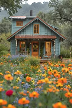 a blue house surrounded by flowers and trees