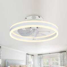 a white ceiling fan sitting above a bed in a bedroom next to a large window