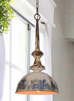 an old light hanging from a ceiling in a room with white walls and windows behind it