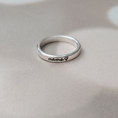 This is a sweet classic sterling silver ring that celebrates the unique bond between a mom and her child! This custom hand-stamped ring is as adorable as it is meaningful, with "mama" or your child's name beautifully stamped one letter at a time onto a shiny silver band, creating a personalized and whimsical keepsake that Mom will cherish. The sterling silver band is crafted with love and care, ensuring a comfortable fit for Mom's finger. The band is designed to be stylish and eye-catching, with Silver Hand Stamped Rings For Mother's Day, Personalized Silver Stackable Rings As Gift, Dainty Sterling Silver Stackable Rings For Mother's Day, Adjustable Engraved Rings For Mother's Day, Adjustable Personalized Sterling Silver Initial Ring, Mother's Day Promise Engraved Ring, Personalized Sterling Silver Initial Ring As Gift, Personalized Sterling Silver Initial Ring For Gift, Custom Name Sterling Silver Stackable Rings As Gift