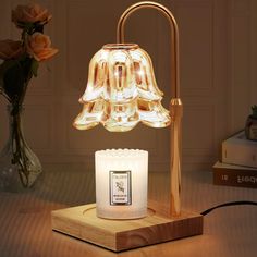 a table lamp that is on top of a wooden block with a flower vase in the background