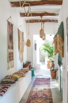 a hallway with rugs hanging from the ceiling and potted plants on the wall