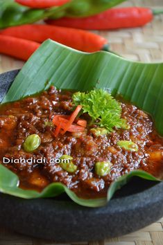 a bowl filled with chili and vegetables on top of a table next to carrots