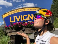 a woman wearing a helmet standing in front of a sign