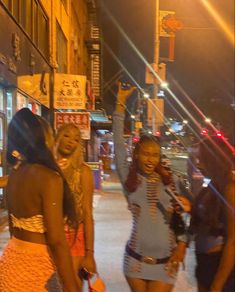 three women walking down the street at night with one holding her hand up in the air