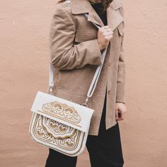 In Morocco, hand embroidery serves as a thread connecting generations, with mothers teaching daughters the craft. Embroidered designs can be found on various items in the souks—from handkerchiefs to poufs and bags—and the designs differ from city to city. This satchel, the perfect size for books, has proven itself a versatile companion for any adventure. 10" tall, 11" wide Detachable shoulder strap Embroidered leather White Rectangular Bag With Machine Embroidery, White Rectangular Bags With Machine Embroidery, Artisan Embroidered Tote Shoulder Bag, Traditional Embroidered Satchel Bag, Traditional White Tote Bag, Traditional White Embroidered Shoulder Bag, White Embroidered Satchel Shoulder Bag, Traditional White Shoulder Bag For Daily Use, Traditional White Shoulder Bag For Travel