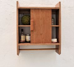 a wooden shelf with various items on it and a white wall in the back ground