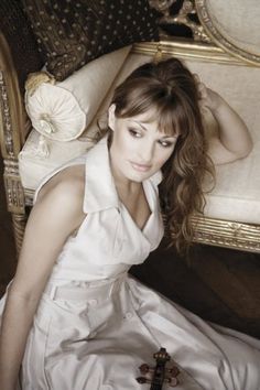 a woman in a white dress sitting on a couch next to a cross and pillow