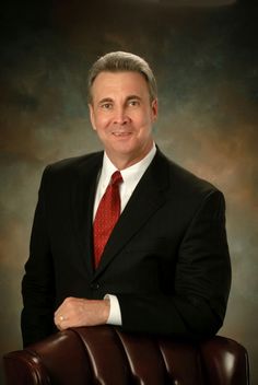 a man in a suit and red tie posing for a photo with his arms crossed