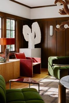 a living room filled with green couches and chairs next to a table in front of two windows