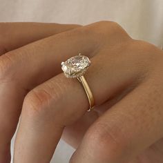 a woman's hand holding an engagement ring with a pear shaped diamond on it