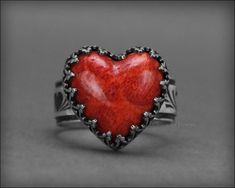 This stunning Red Coral Heart Ring is designed to make a bold statement with its vibrant red color. Perfect as a gift for your sweetheart! The heart is made from a red coral composite, crafted from coral cuttings and pigmented resin. It’s set in a sterling silver gallery bezel with an inverted heart design. The wide sterling silver band features a charming heart pattern, and the ring is oxidized to highlight all the intricate details. Specifications: sold individually made-to-order* materials: s Lauren Elizabeth, Ring Shank, The Coral, Composite Material, Heart Pattern, Sterling Silver Bands, Wide Bands, Red Coral, Heart Patterns