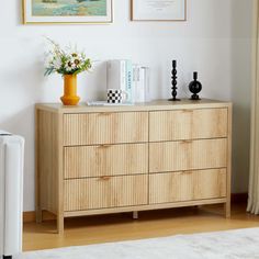 a wooden dresser with two vases on top of it next to a white rug