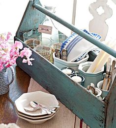 a wooden box filled with dishes and utensils sitting on top of a table