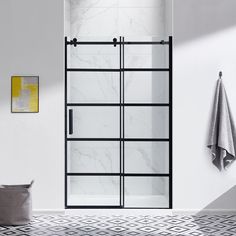 a white bathroom with marble tile flooring and black glass shower door, next to a gray towel rack on the wall