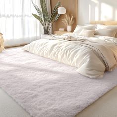 a large bed with white sheets and pillows in a bedroom next to a plant on the floor