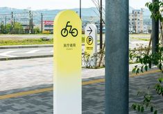 a yellow and white sign sitting on the side of a road next to a pole