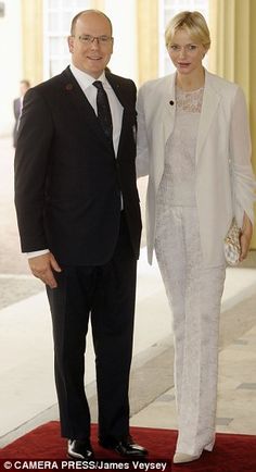 a man and woman in formal wear standing on a red carpet