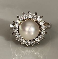 Classic White Pearl Ring With Diamond Accents, White Gold Pearl Ring With Diamond Center Stone, Classic Oval Pearl Ring With Diamond Accents, Timeless Diamond Pearl Ring With Center Stone, Classic White Cluster Ring With Halo, White Pearl Ring With Prong Setting For Formal Occasions, Formal White Pearl Ring With Prong Setting, Classic Pearl Ring With Diamond Center Stone, Classic Pearl Ring With Diamond