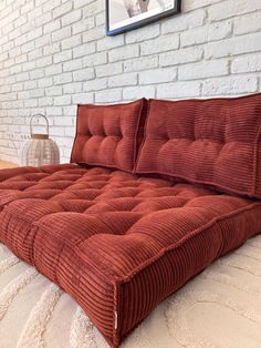 a bed that has been made with red corded material and pillows on top of it