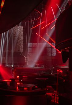 red and white lights shine brightly in the dark room with round tables on either side