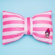 a pink and white bow tie with hello kitty on it's side sitting on a blue surface