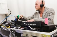 a man with headphones on sitting in front of an electronic equipment box that has wires attached to it