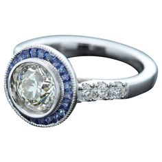 Art Deco Style Bold Ring Center is 1.25 carat Diamond surrounded with Blue Sapphire, sides have regular small white Diamonds All stones are Natural 18k White 5.70 grams Center Diamond is a Brilliant J-K color and SI2-I1 clean however has a very good sparkle (8.0 mm) set in a cup setting Small Diamonds 0.37 carat Blue Sapphire 0.63 carat Finger size 7 overall surface area diameter size - 12mm Round Platinum Diamond Ring With Halo Design, Platinum Round Diamond Ring With Halo Design, Classic Round Multi-stone Jewelry, 14k White Gold Halo Ring In Diamond White, White Multi-stone Platinum Jewelry, Round Multi-stone Diamond Sapphire Ring, Classic White Sapphire Round Ring, Classic White Round Sapphire Ring, Multi-stone Sapphire Ring With Diamonds