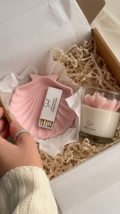 a person is holding a candle and some candles in a box with the lid open