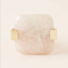 a large white stone with two gold squares on the front and back of it, against a white background