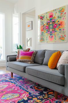 a gray couch with colorful pillows on top of it in front of a large window